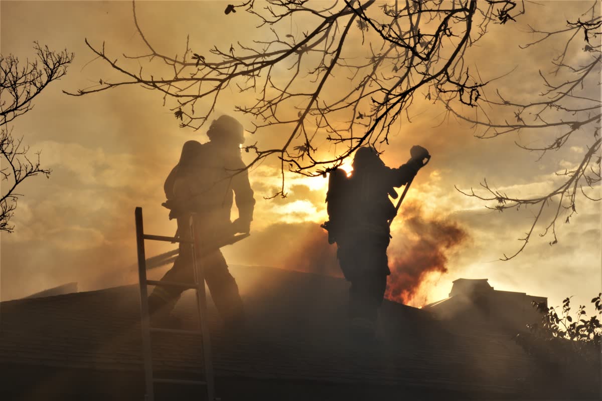 Firefighters on a roof at sunset